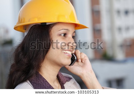 Happy female construction engineer talking on cellphone