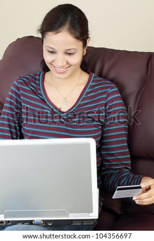 Happy Indian woman with laptop and a credit card