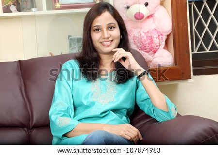 Young happy indian woman sitting on sofa