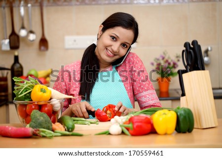 Young woman talking on cellphone in her kitchen