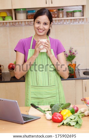 Young Indian woman drinking coffee in her kitchen