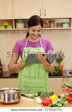 Young Indian woman using a tablet computer in her kitchen