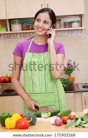 Young Indian woman working with tablet and talking on cellphone