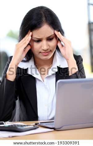 Stressed young business woman with tablet computer at office