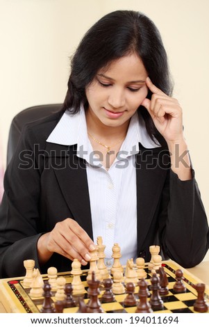 Young female business woman playing chess