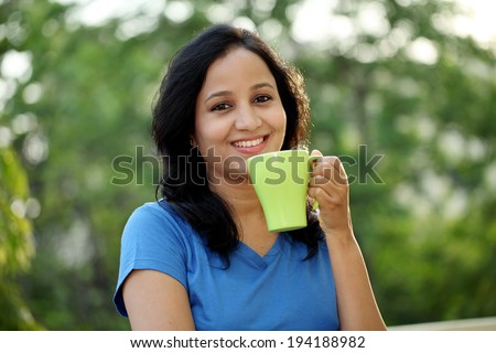 Happy young woman drinking coffee at outdoors