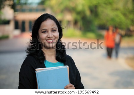 Young female student at college campus and carrying books