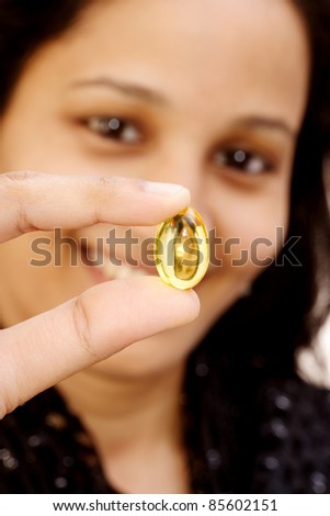 woman holding a yellow vitamin capsule,