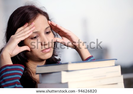 Stressed student with stack of booksn