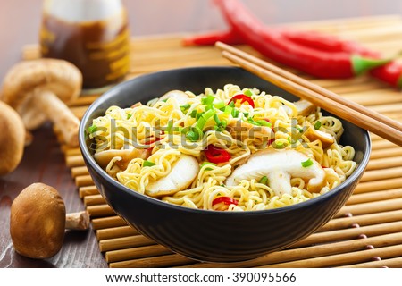 Instant noodles with shiitake mushrooms, pepper and onion in a bowl, Asian meal on a table