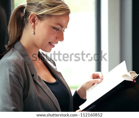 Profile of a beautiful blonde woman immersed in reading a book with a small smile of pleasure on her lips