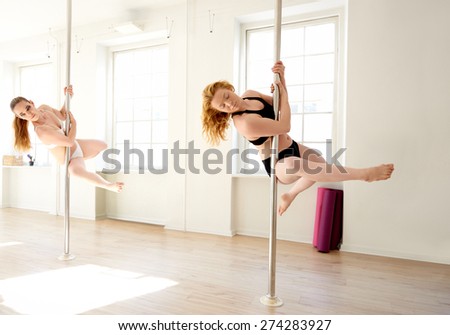 female pole dancer holding a pole with both hands and her body perpendicular to the pole with one leg stretched and one leg bent backwards