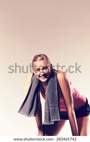 Fit woman exercising and leaning over with hands on knees and towel around neck. Image with copyspace for text