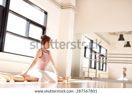 Young Ballering Wearing Pink Tutu Doing Splits in Sunny Dance Studio and Monitoring Posture in Reflection in Mirror