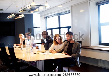 Group of young executives working and sitting at table in conference room