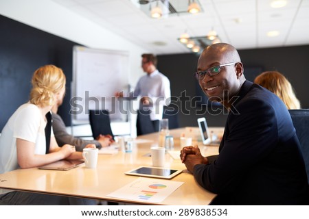 Black male executive smiling at camera during a work presentation