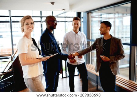 Group of young executives in modern space smiling and making introductions.