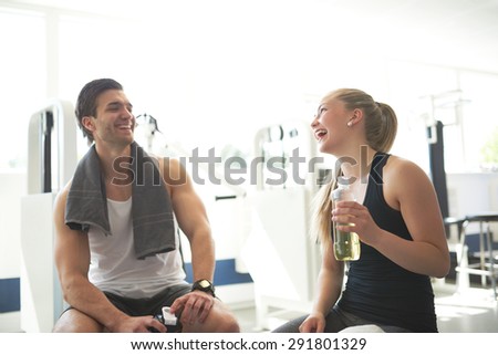 Young Healthy Couple Relaxing After Workout In the Gym with Happy Facial Expressions.