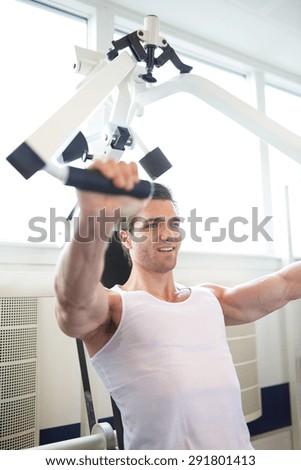Handsome Muscular Guy in White Sleeveless Shirt, Doing Chest Press Exercise using a Machine Inside the Gym