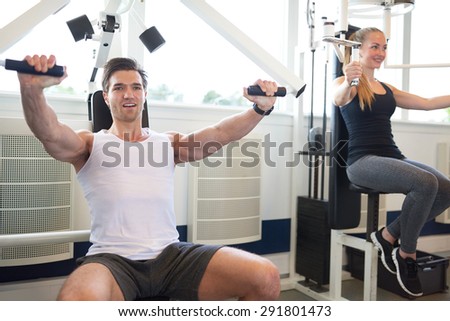 Handsome Athletic Gym Instructor Doing a Chest Press Exercise Beside a Young Woman Student Inside the Gym.