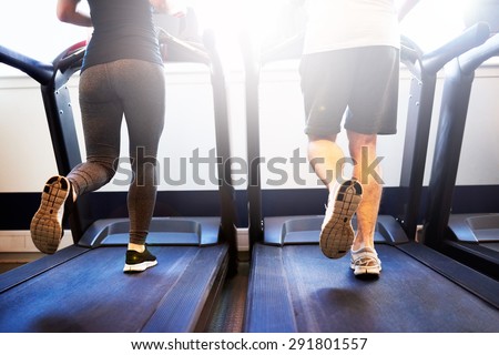 Lower Body Shot of Healthy Athletic Couple Running on Treadmill Machine Inside the Fitness Gym
