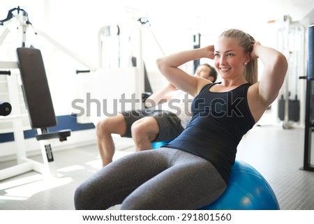 Happy Fit Young Woman Doing Sit-ups Workout on Exercise Ball While Smiling Into Distance Inside the Gym