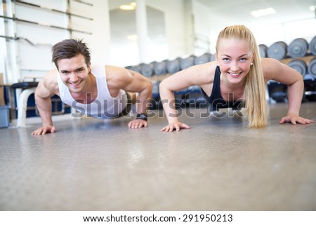 Low Angle View of Couple Doing Push Ups Together or Planking in Gym, Front View of Happy Healthy Couple Working Out Together