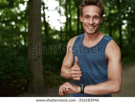 Half Body Shot of a Smiling Fit Guy at the Park Showing Thumbs up and a Hand with Wrist Watch at the Camera.