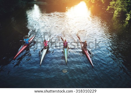 Team of rowing people sailing against camera in sunset