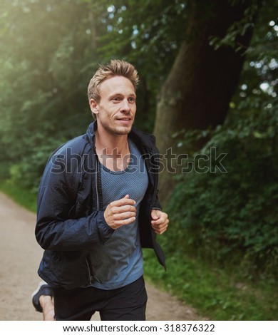 Three Quarter Shot of a Physical Fit Man Running at the Park Early in the Morning with Happy Facial Expression.