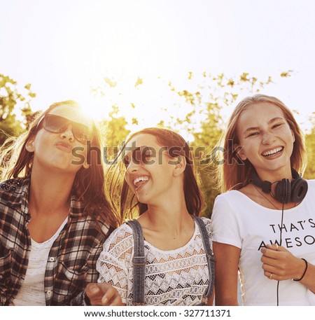 Three teenage girls laughing hanging out on a summer day