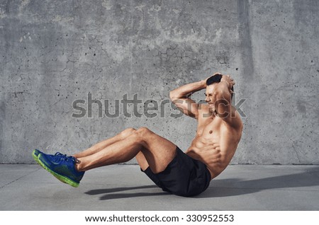 Fitness model exercising sit ups and crunches. Muscular well build, toned body with six pack sweating. Copy space