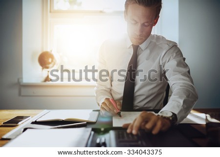 Executive business man working on accounts while being concentrated and serious, wearing white shirt and tie