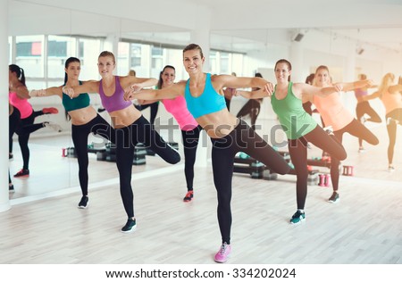 Large colorful group of fit young women working out in a gym doing aerobics exercises in a health and fitness concept