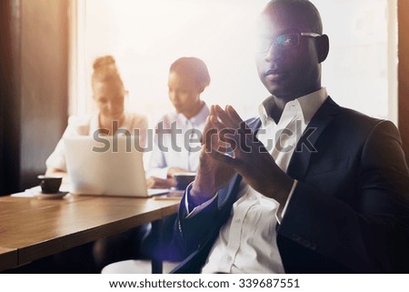Serious black business man sitting in front of his employees at office