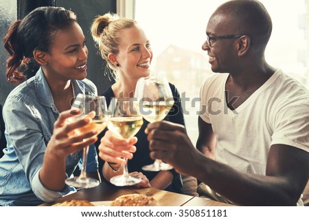 Ethnic friends at a bar drinking wine and eating tapas