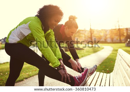Two girlfriends stretching in sunny park