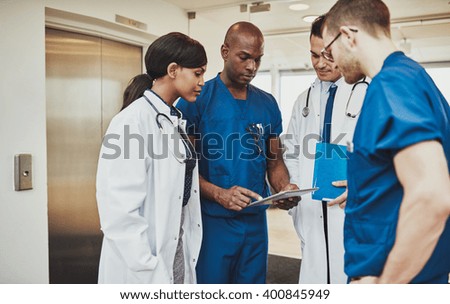 Black surgeon giving instruction to medical team mixed races using tablet
