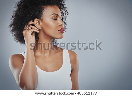 Beautiful woman with big black hair white shirt, Black woman, with closed eyes touching her hair, isolated on grey