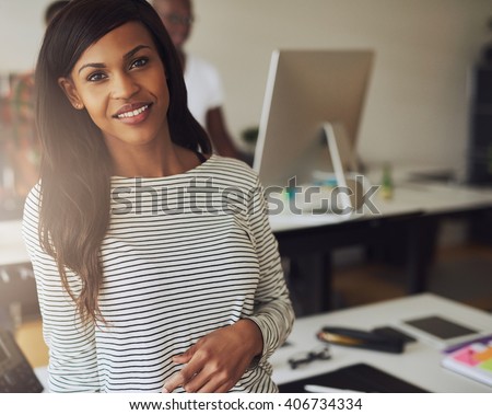Single gorgeous female business owner wearing black and white striped blouse with partner on computer in background