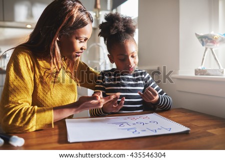 Black mom and child doing homework at kitchen