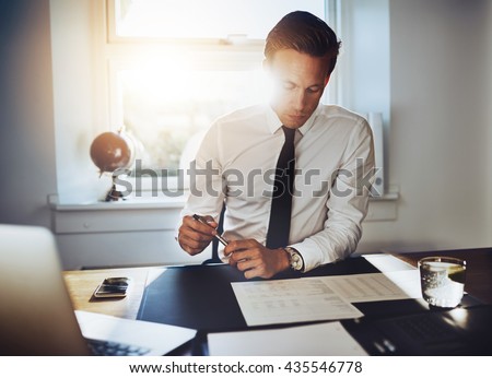 Executive business man working at desk in a classic office while wearing a suit and tie
