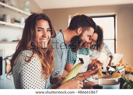 Laughing woman talking and preparing meals at table full of vegetables and pasta ready for cooking in kitchen