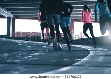 Rear view of unrecognizable sportsmen running in parking place. Copyspace