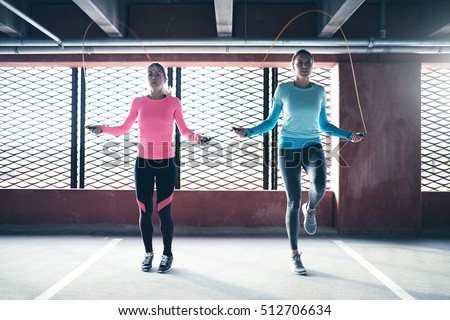 Front view of two athletic girls doing jump rope exercise. Copyspace