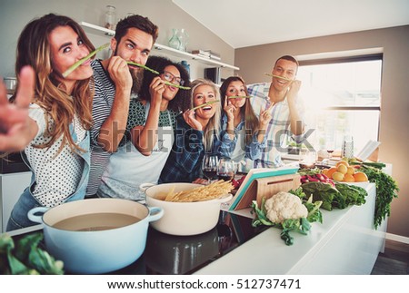 Five friends having a little break to fool around with some asparagus while cooking