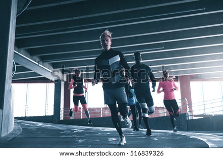 Front view of sportive man running towards camera with his team-mates. Copyspace