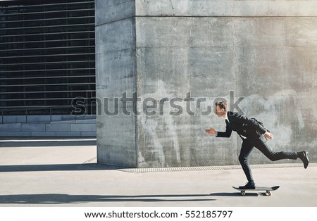 Side view of a man in black suit on a skateboard going fast