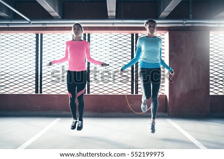 Young pretty athletics girls skipping on drill at gym against barred window.