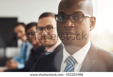 Handsome black business man with three employees and back to large bright office window with light flare